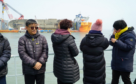 28일 오전 전남 진도군 세월호 사고해역 인근 선박 위에서 열린 미수습자의 조기 수습을 기원하는 4대 종단 종교행사가에 참석한 미수습자 가족들이 세월호를 바라보며 눈물을 훔치고 있다. 해양수산부 제공